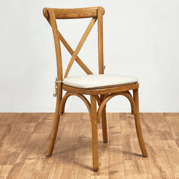Wooden oak chair with a light cream coloured tie-on cushion on a wooden floor.